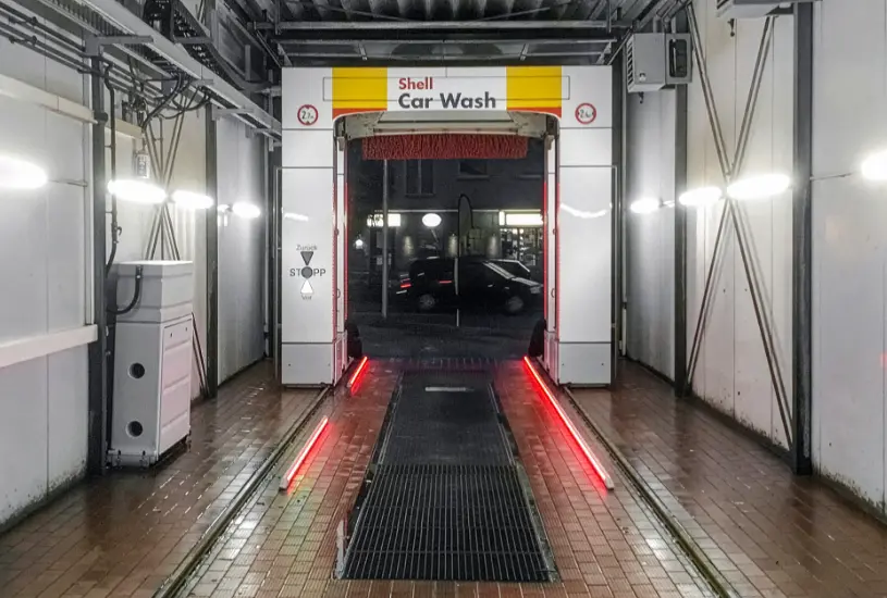 Waschanlage vor Sanierung, ohne Wandverkleidung, mit dunklem Kachelboden